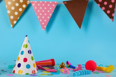 Photo of Colorful party hats and other festive items on light blue background. Space for text