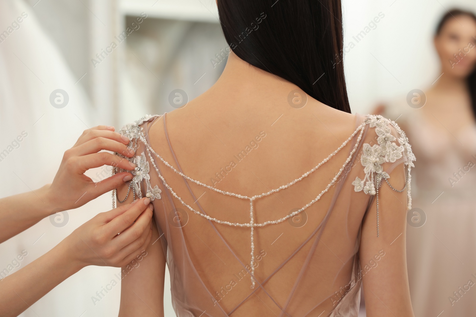 Photo of Woman trying on beautiful wedding dress in boutique, back view