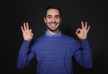 Photo of Man showing OK gesture in sign language on black background