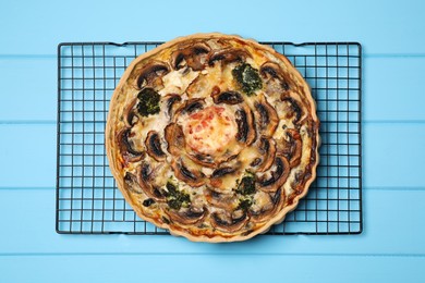 Photo of Delicious quiche with mushrooms on light blue wooden table, top view