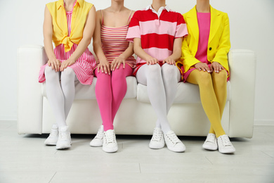 Photo of Women wearing colorful tights sitting on sofa indoors, closeup