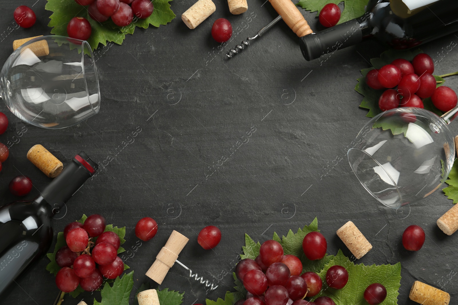 Photo of Frame of tasty red wine and grapes on black table, flat lay. Space for text