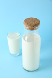 Carafe and glass of fresh milk on light blue background