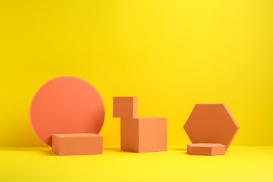 Photo of Many orange geometric figures on yellow background. Stylish presentation for product
