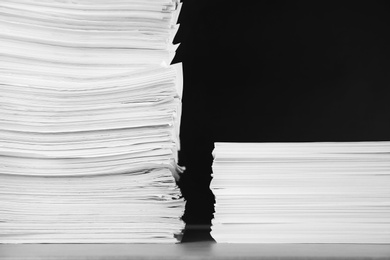 Photo of Stacks of blank paper on grey stone table against black background