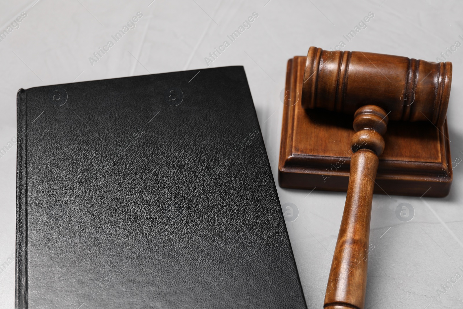 Photo of Law. Book, gavel and sound block on light table, closeup