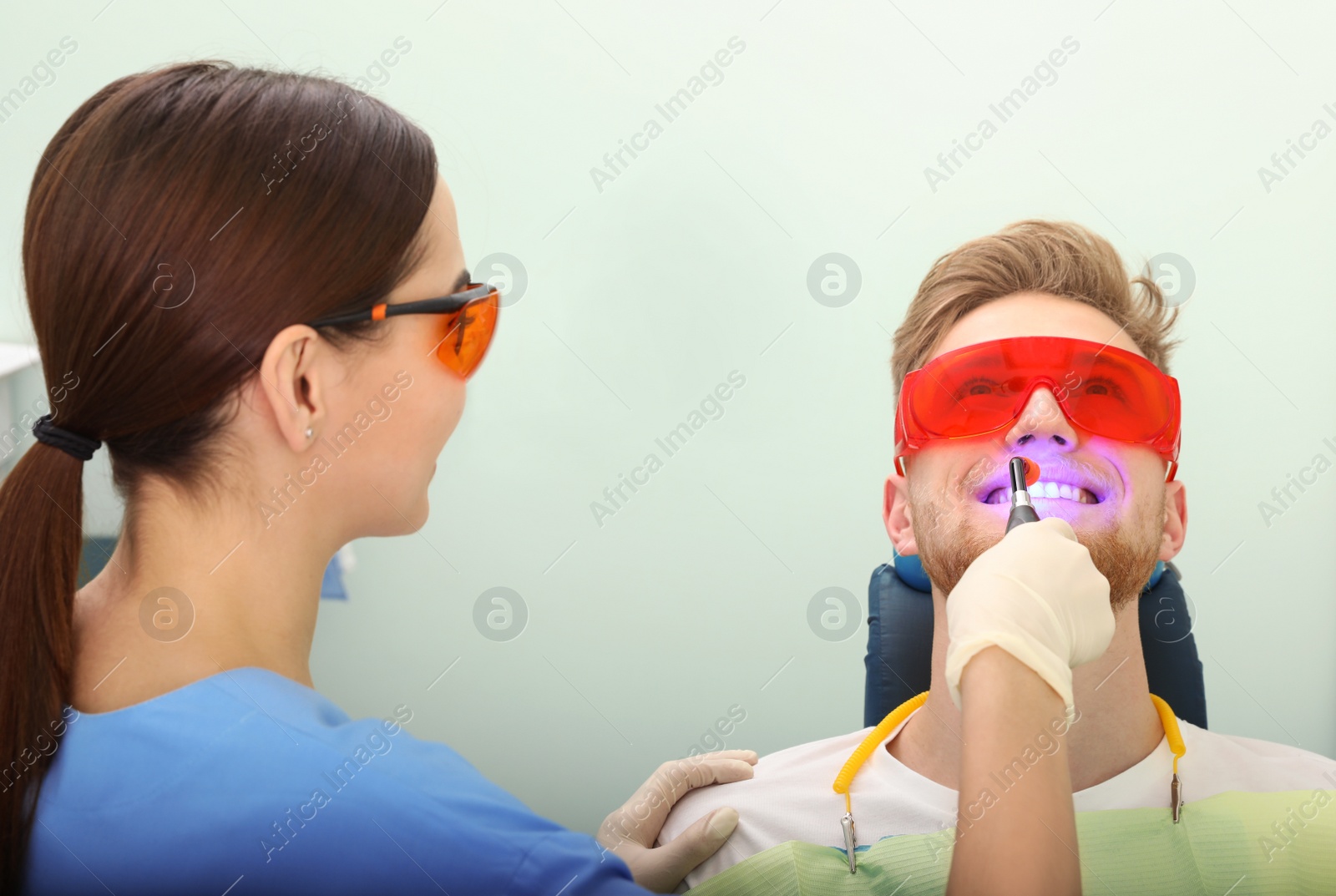 Photo of Professional dentist working with patient in modern clinic. Teeth whitening