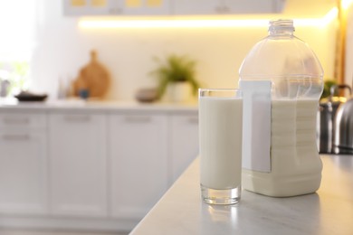 Photo of Gallon bottle of milk and glass on white countertop in kitchen. Space for text