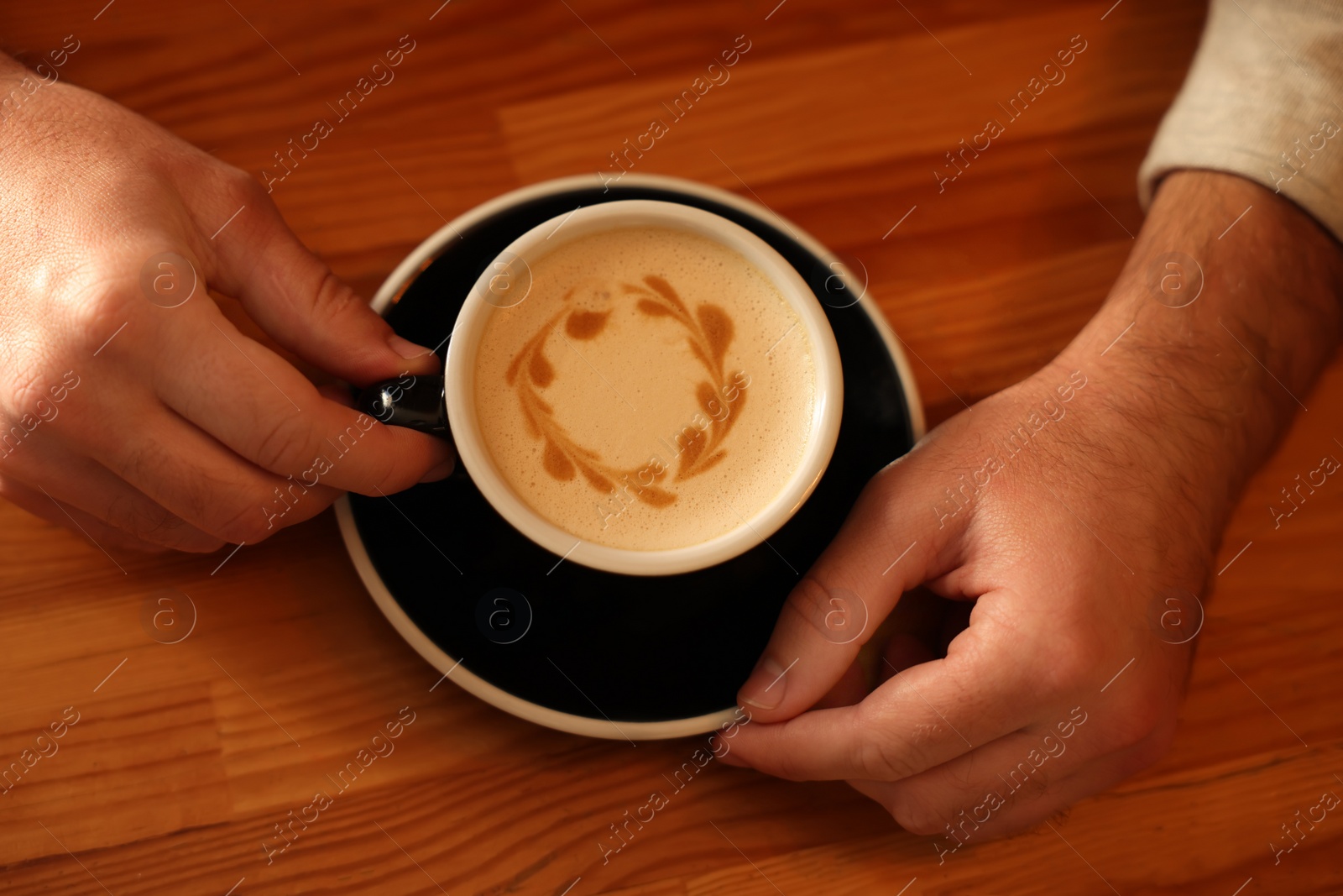 Photo of Man with cup of aromatic coffee at wooden table, above view