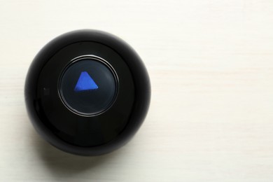 Photo of Magic eight ball on white table, top view. Space for text