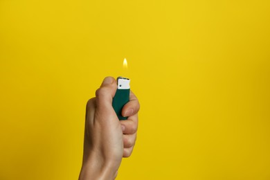Photo of Woman holding green lighter on yellow background, closeup. Space for text