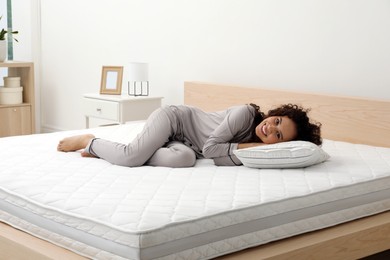 Photo of Happy young African American woman on bed with comfortable mattress and pillow at home