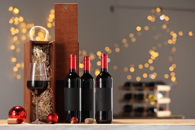 Bottles of wine, glass, wooden gift boxes, corks and red Christmas balls on table