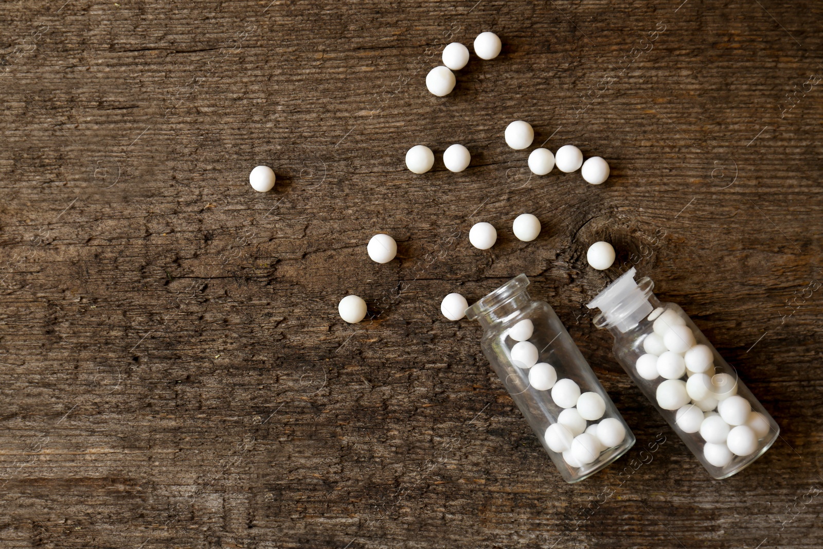 Photo of Bottles of homeopathic remedy on wooden background, flat lay. Space for text