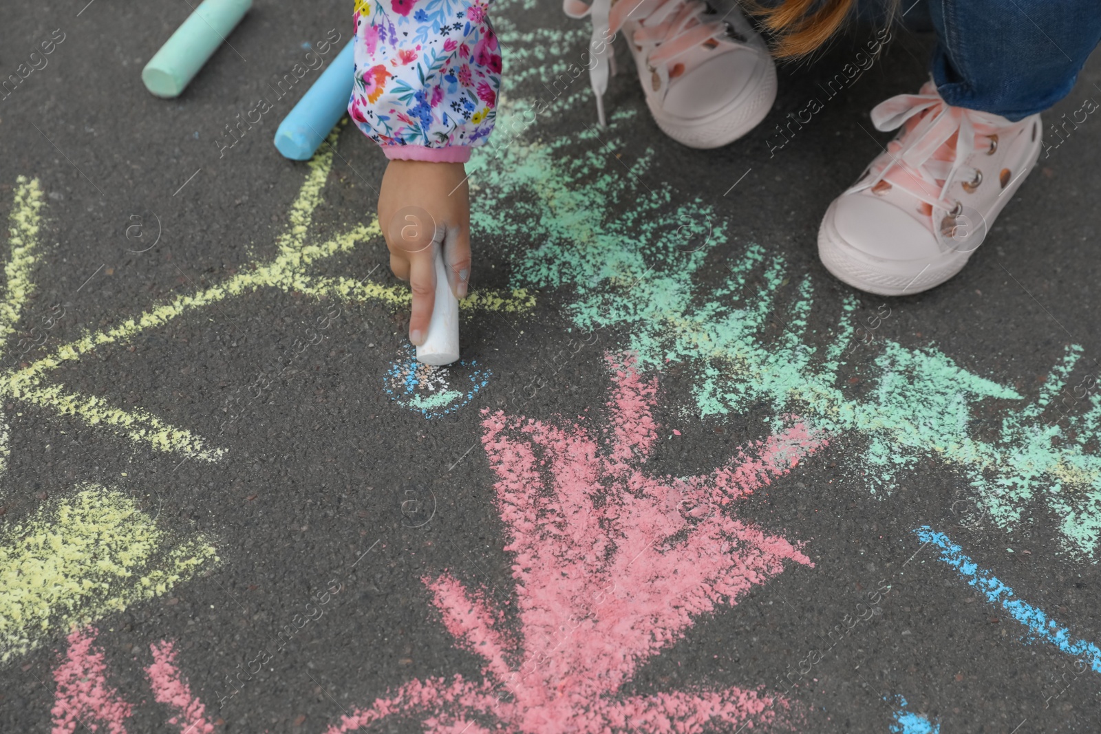 Photo of Child drawing family with chalk on asphalt, closeup