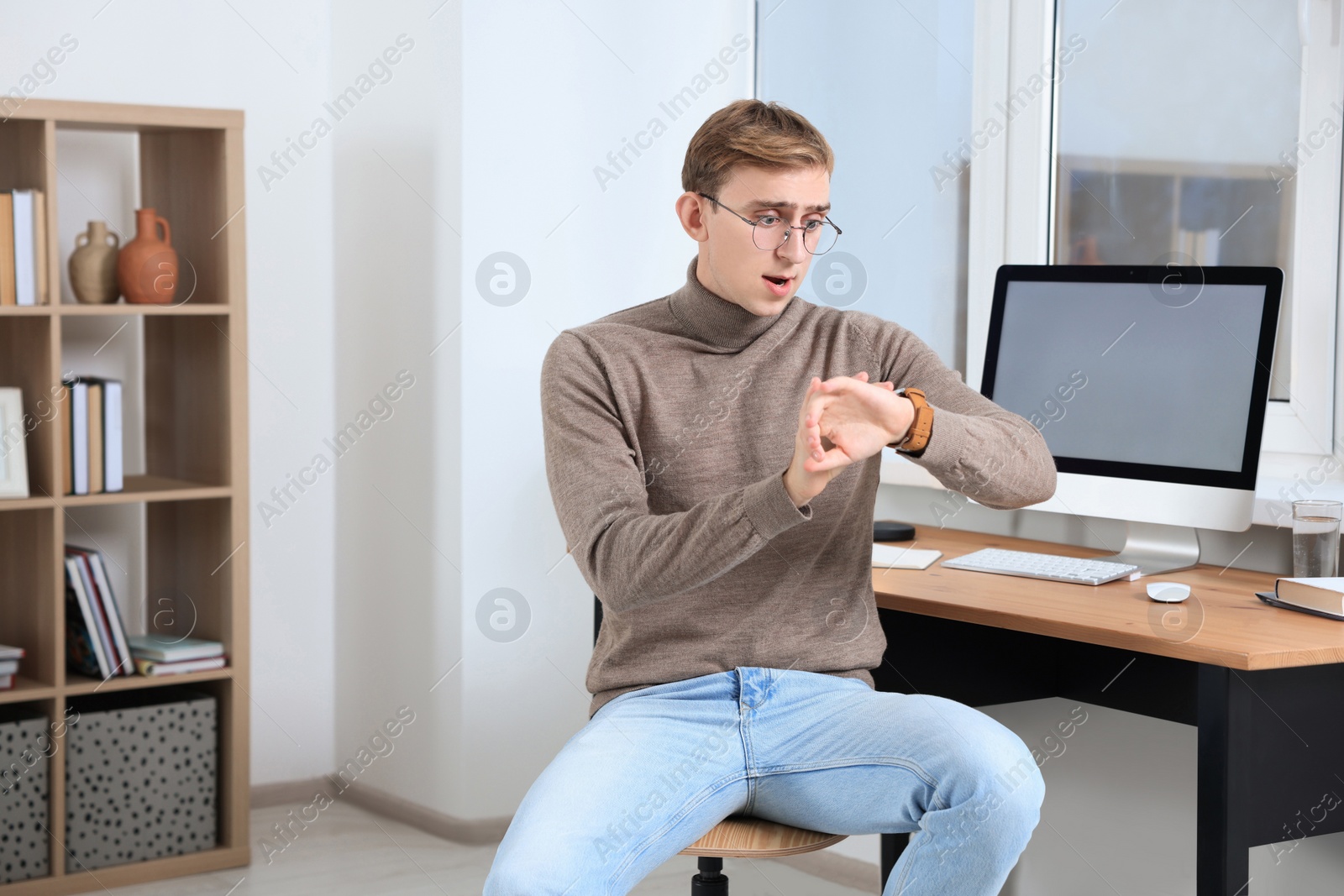 Photo of Emotional young man checking time in office. Being late