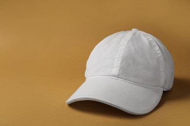 Photo of Baseball cap on brown background, space for text