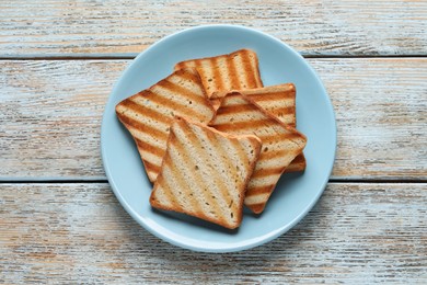 Photo of Plate with slices of delicious toasted bread on wooden table, top view