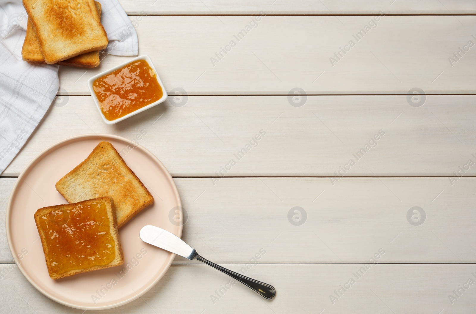 Photo of Toasts and orange jam served on white wooden table, flat lay. Space for text