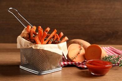 Photo of Sweet potato fries and ketchup on wooden table
