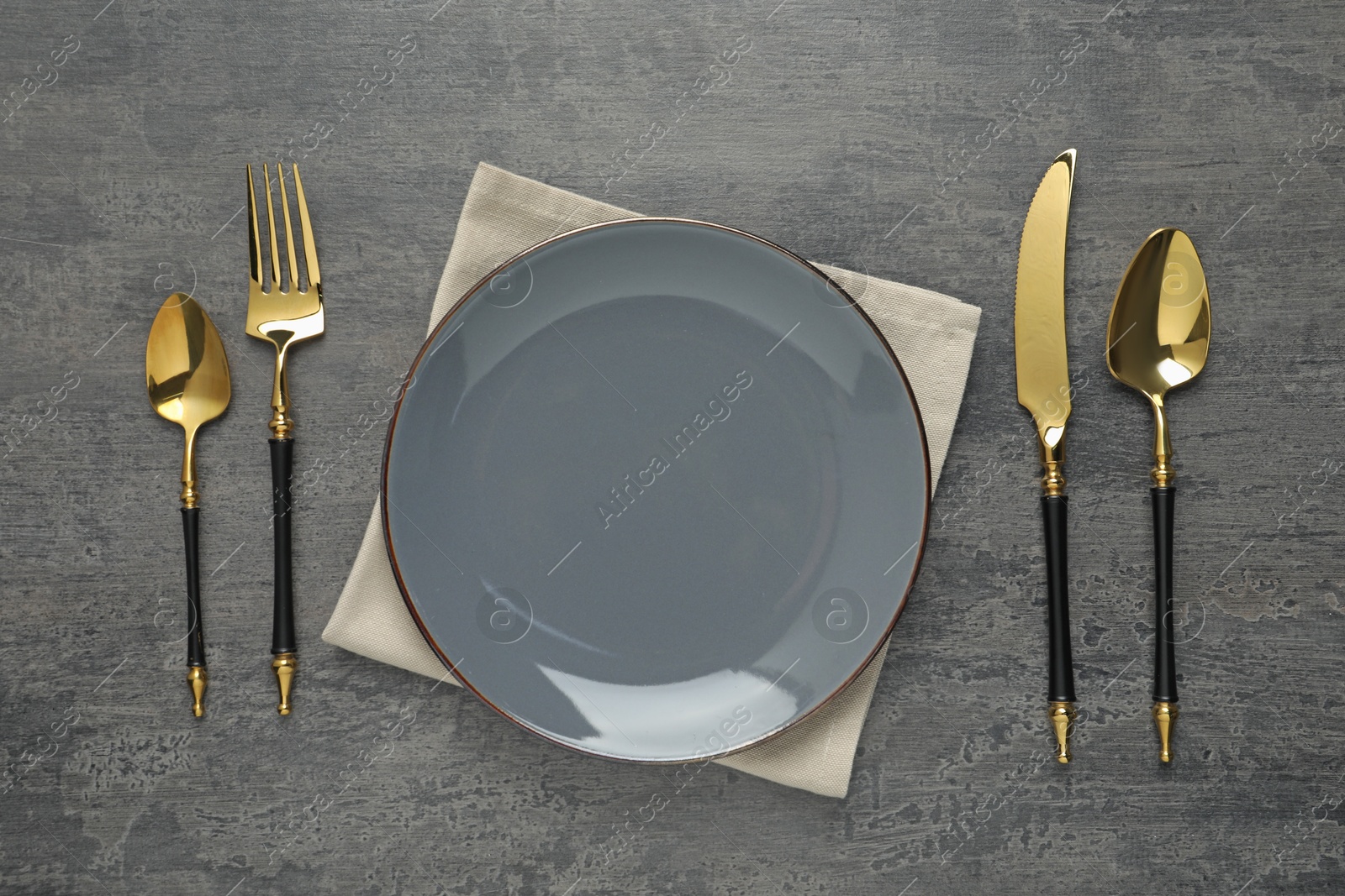 Photo of Elegant setting with golden cutlery on dark grey table, flat lay