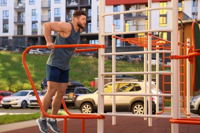 Photo of Man training on parallel bars at outdoor gym
