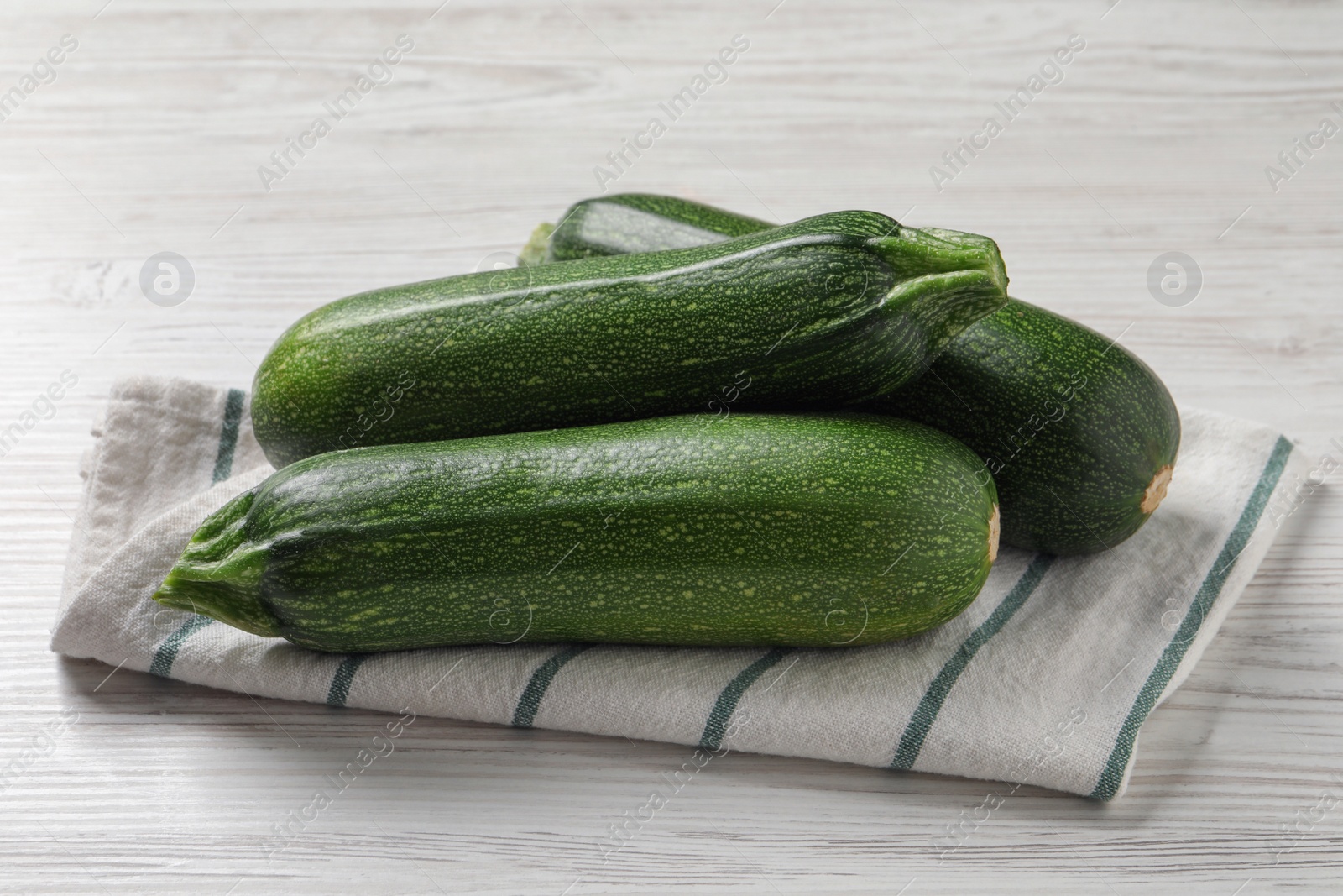 Photo of Raw ripe zucchinis on white wooden table