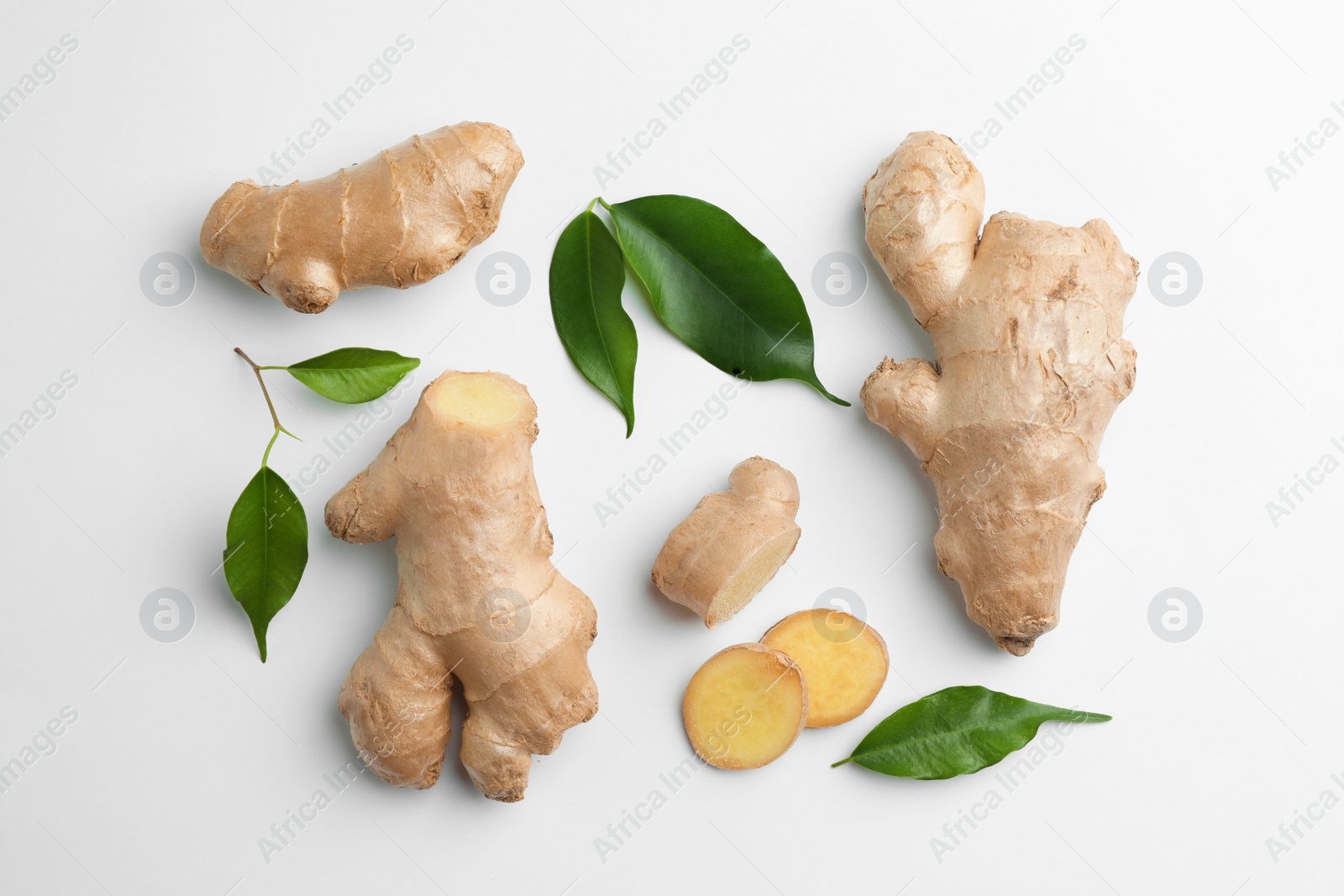 Photo of Fresh ginger with green leaves on white background, flat lay