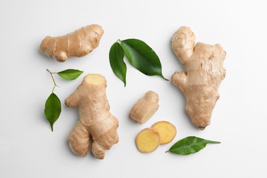 Photo of Fresh ginger with green leaves on white background, flat lay