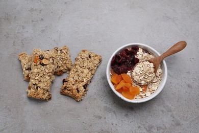 Photo of Tasty granola bars and ingredients on grey table, flat lay