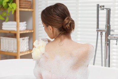 Photo of Woman taking bath with shower gel in bathroom