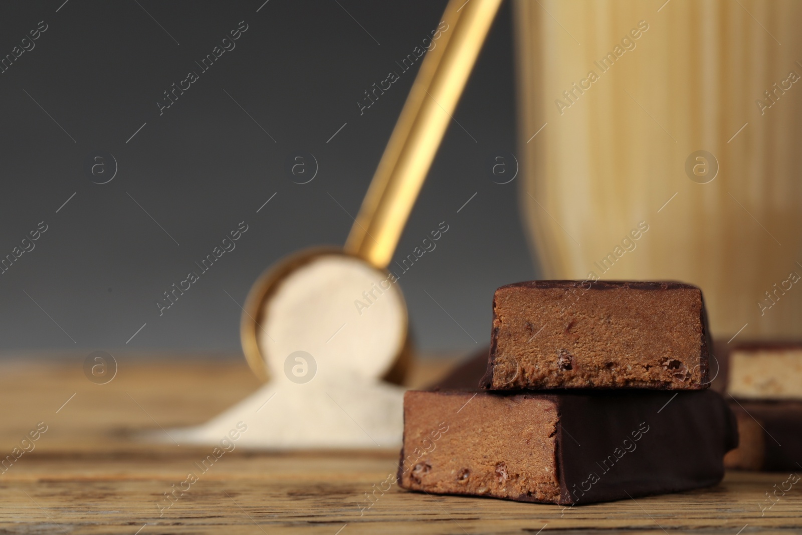 Photo of Energy bars, protein cocktail and powder on wooden table, closeup. Space for text