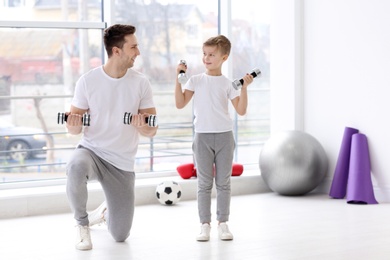 Photo of Dad and his son training with dumbbells in gym