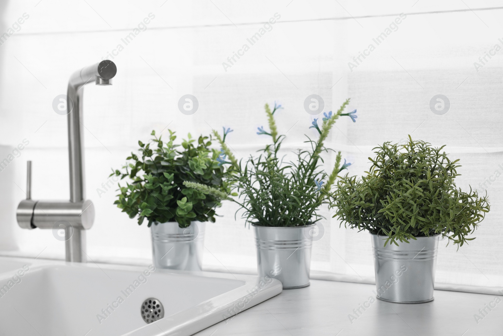 Photo of Different potted artificial plants on countertop in kitchen. Home decor