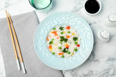 Photo of Boiled rice with vegetables served on marble table, flat lay