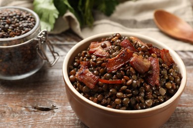 Delicious lentils with bacon in bowl on wooden table, closeup