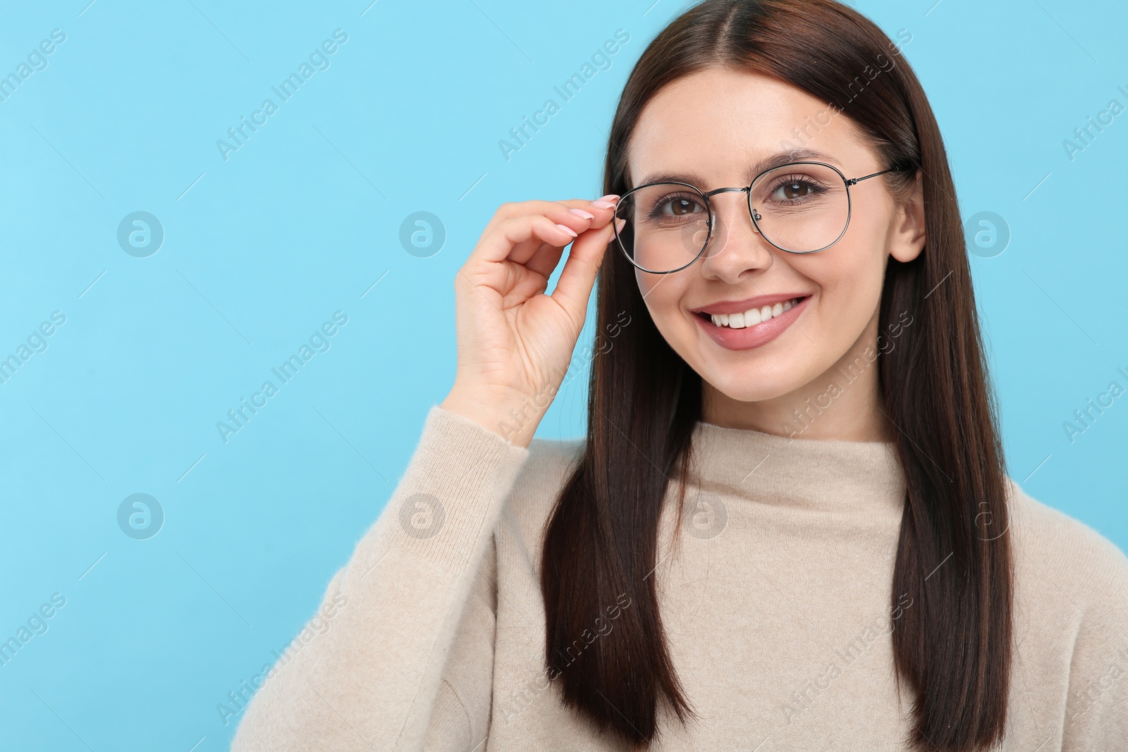 Photo of Portrait of smiling woman in stylish eyeglasses on light blue background. Space for text