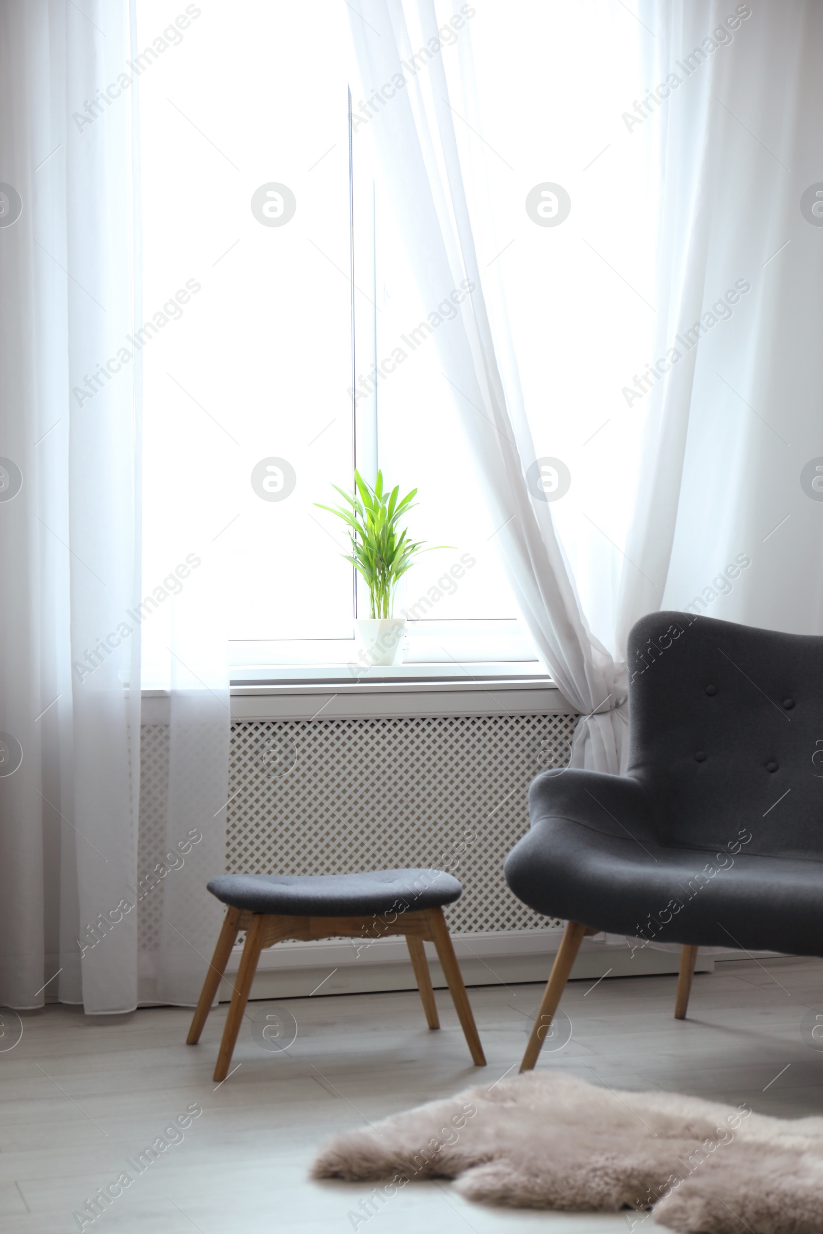 Photo of Comfortable sofa near window with open curtains in elegant room interior