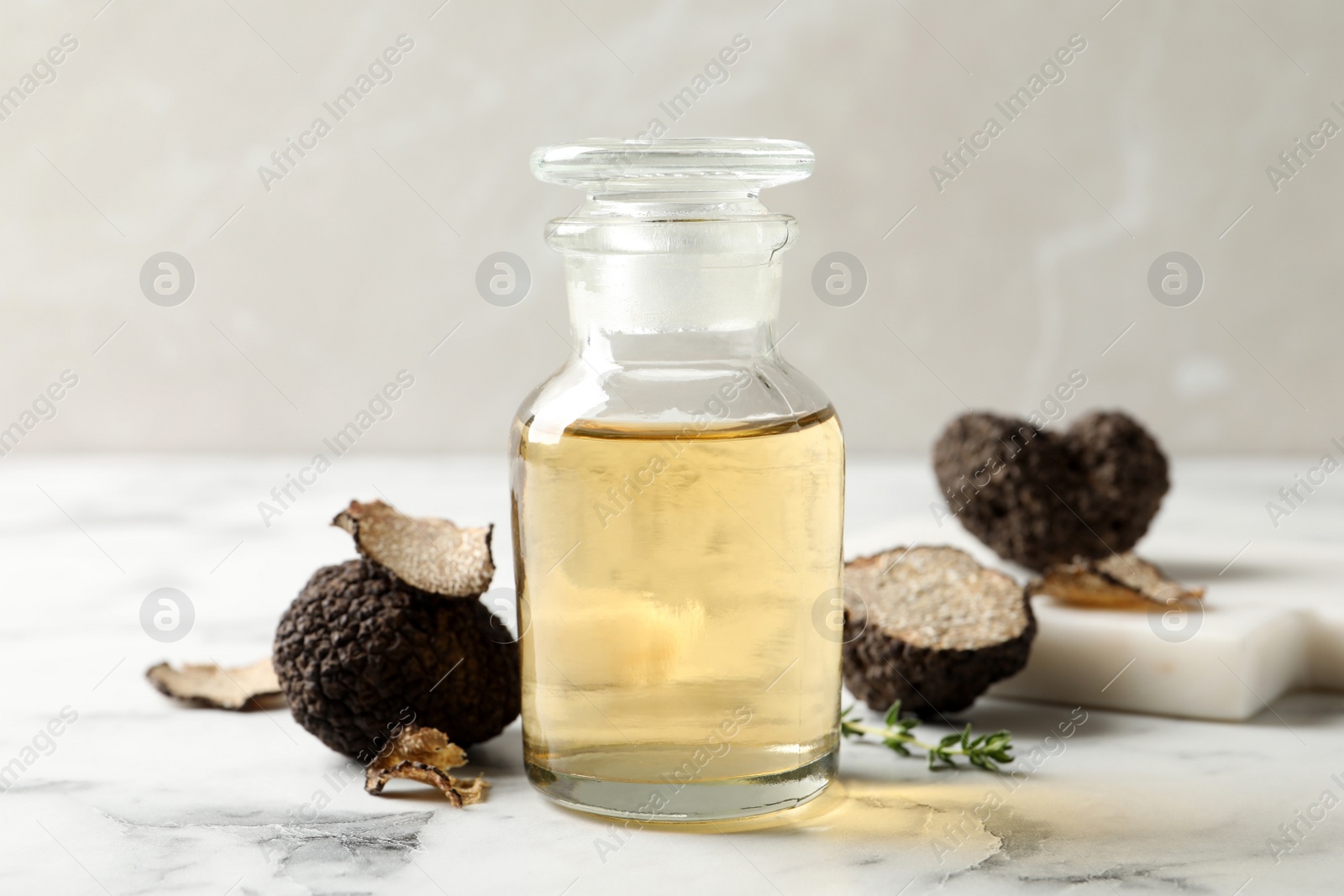 Photo of Fresh truffle and oil on white marble table, closeup