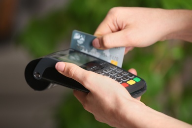 Woman using modern payment terminal indoors, closeup