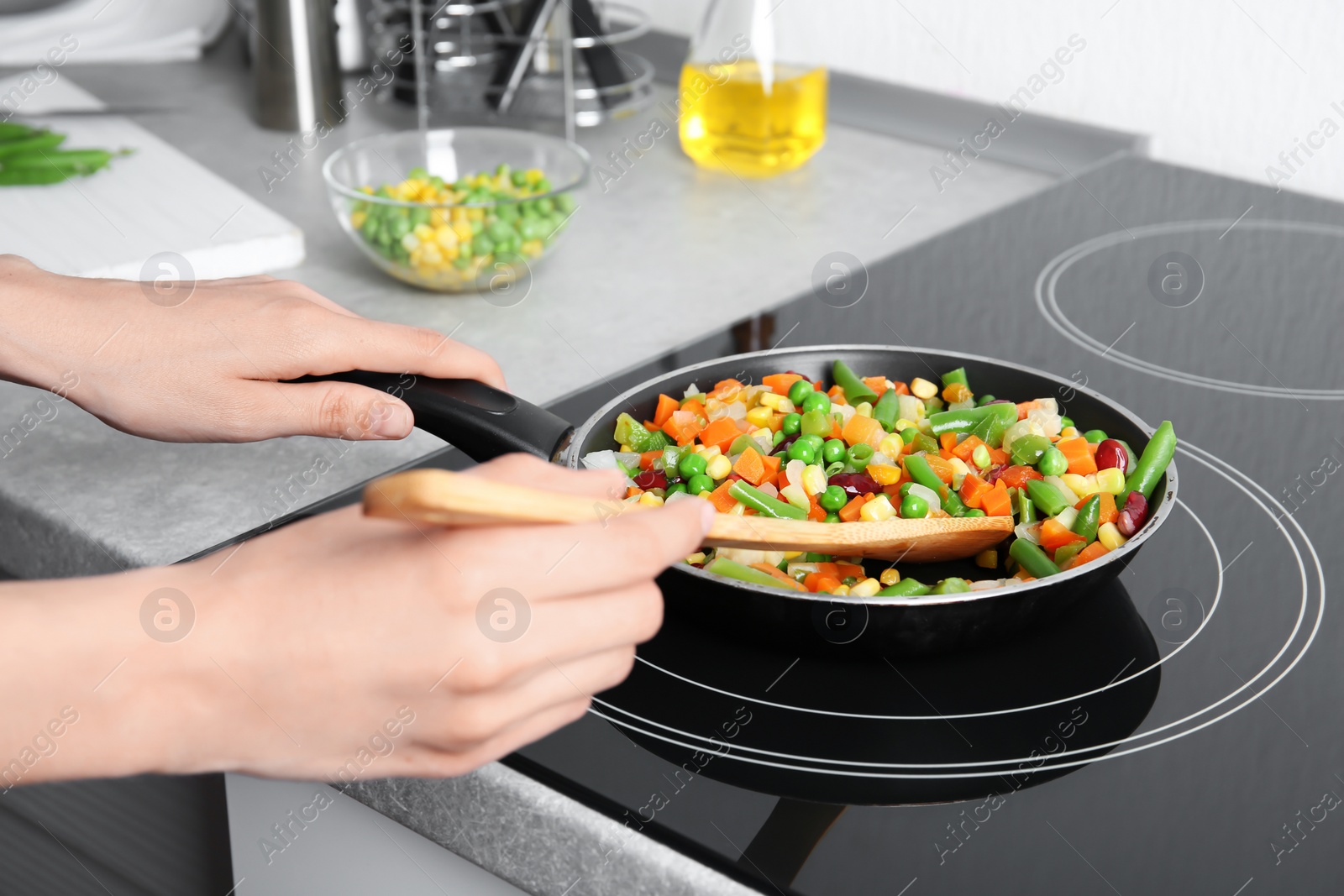 Photo of Woman stirring frozen vegetables on frying pan, closeup