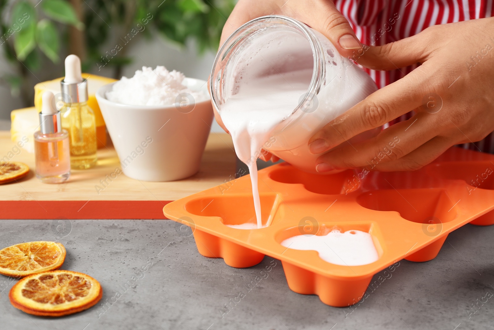 Photo of Woman making natural handmade soap at grey stone table, closeup