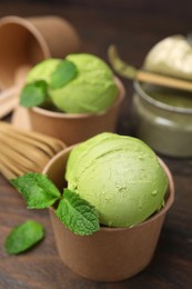 Photo of Paper cups with tasty matcha ice cream on wooden table, closeup