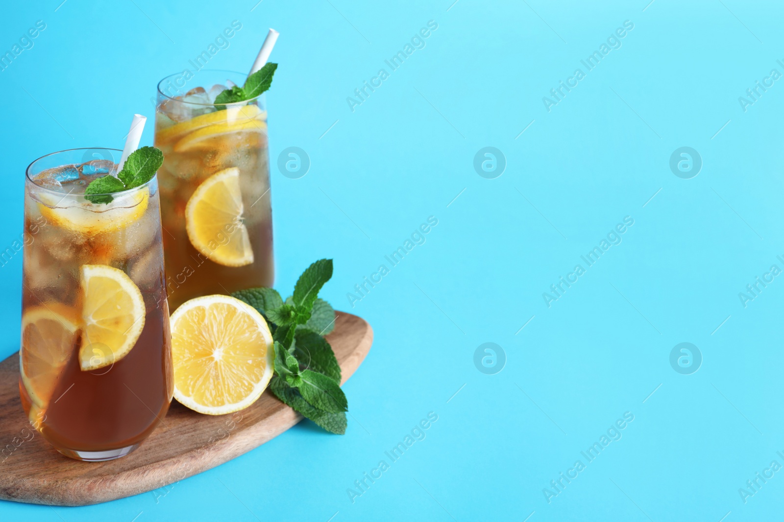 Photo of Delicious iced tea with lemon and mint on light blue background. Space for text