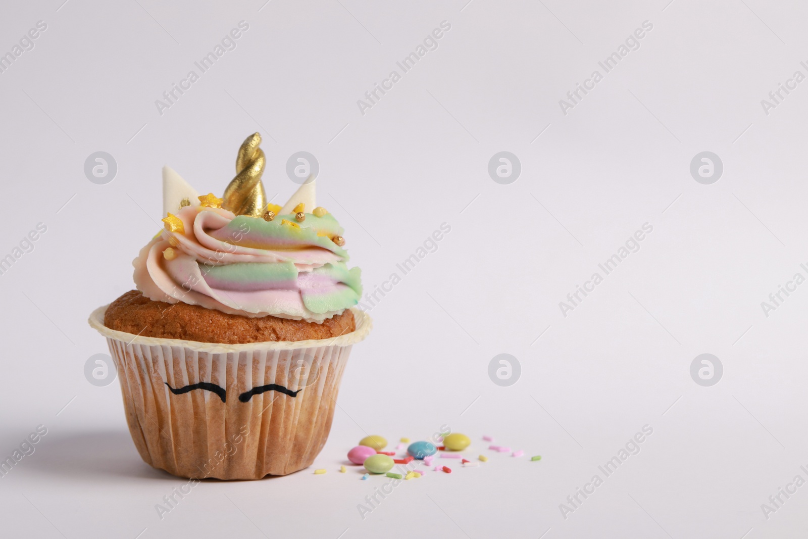 Photo of Cute sweet unicorn cupcake on white background, space for text