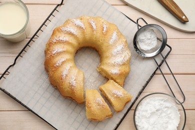 Photo of Delicious sponge cake with powdered sugar and glass of milk on wooden table, flat lay