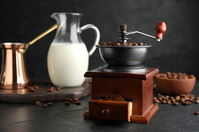 Photo of Vintage manual coffee grinder with beans and powder on black table