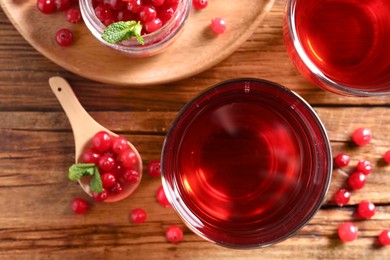 Photo of Tasty cranberry juice in glasses and fresh berries on wooden table, flat lay