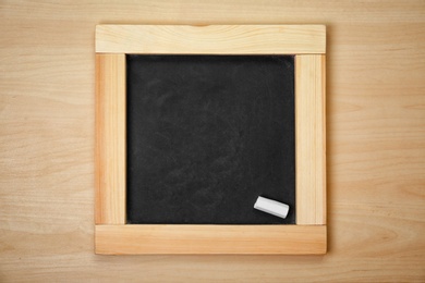 Photo of Clean blackboard with chalk on wooden background