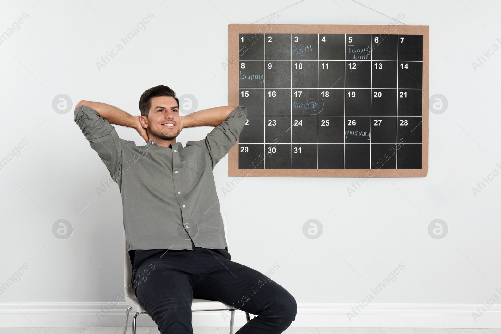 Photo of Handsome man sitting near board calendar indoors